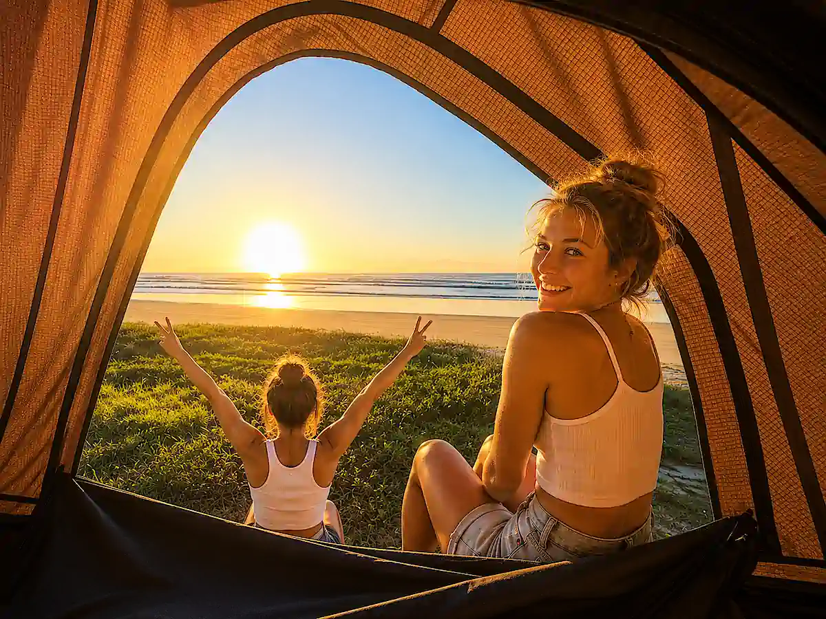 Deux voyageuses dans une tente de toit avec vue sur le lever du soleil pendant leur voyage en 4x4 en Australie